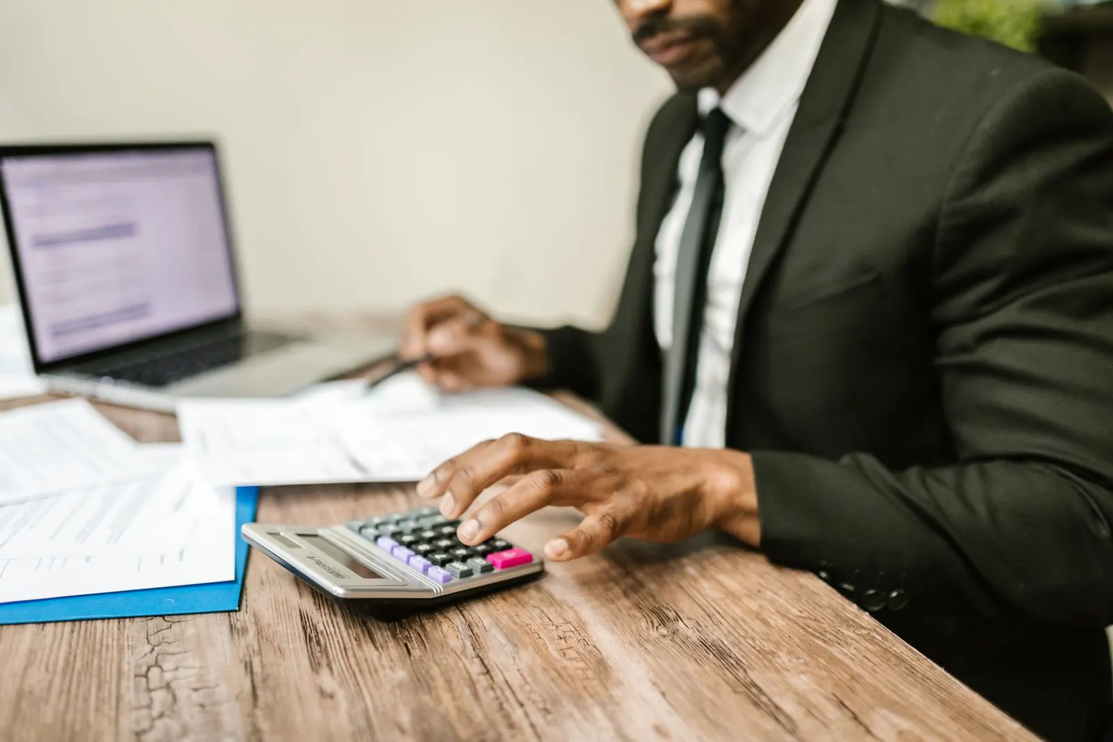 Un hombre de traje trabajando con una calculadora y papeles