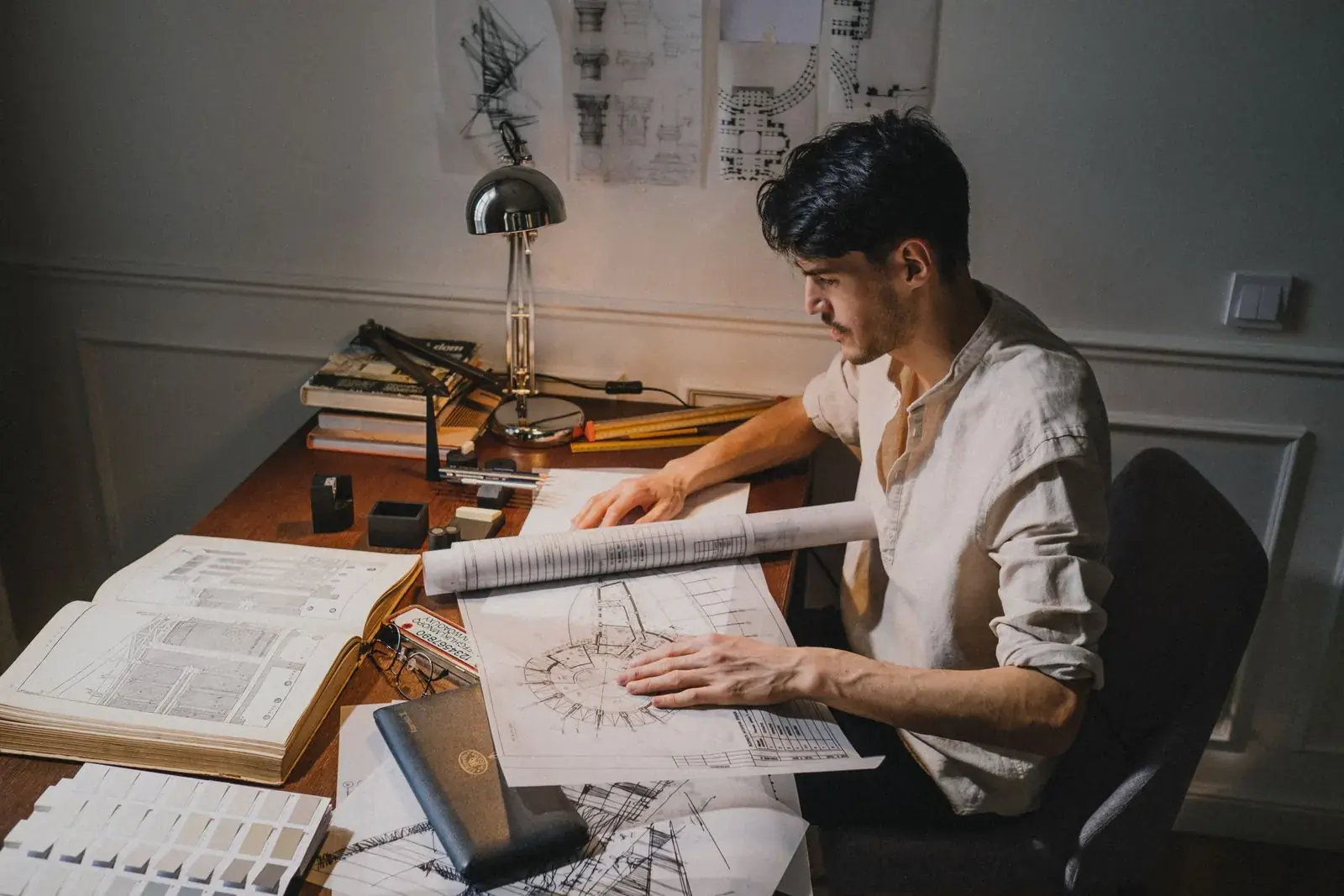 Un hombre dibujando planos en un escritorio de un estudio