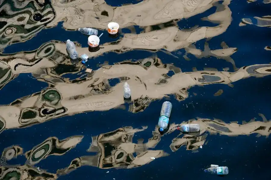 Botellas de plástico y basura flotando en un curso de agua