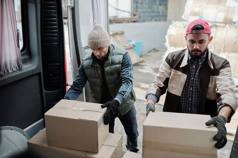 Dos trabajadores cargando cajas en una camioneta de reparto