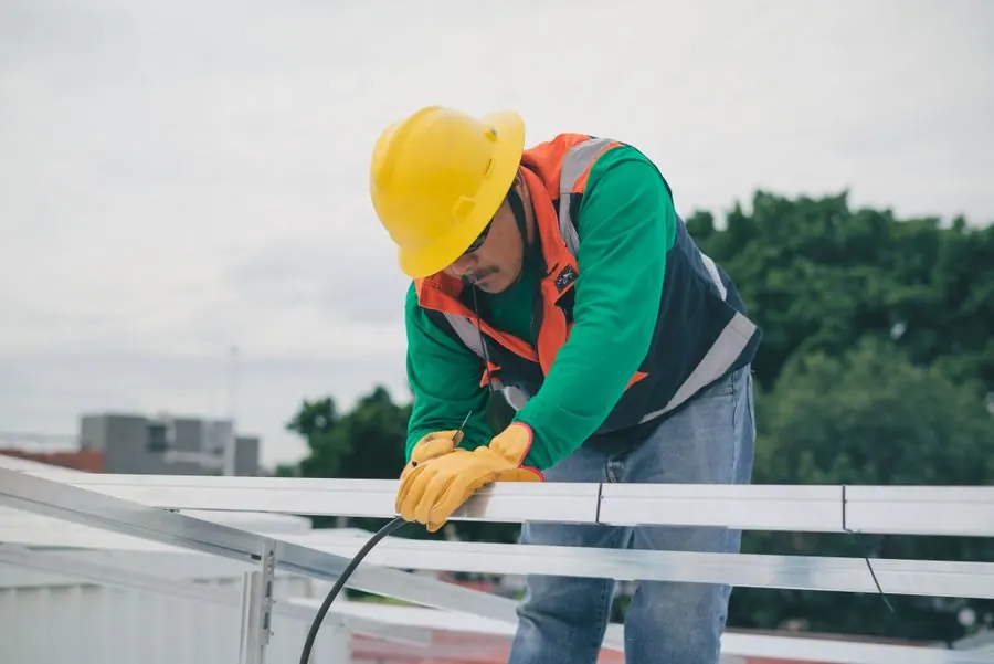 Un trabajador con equipo de seguridad instalando paneles solares