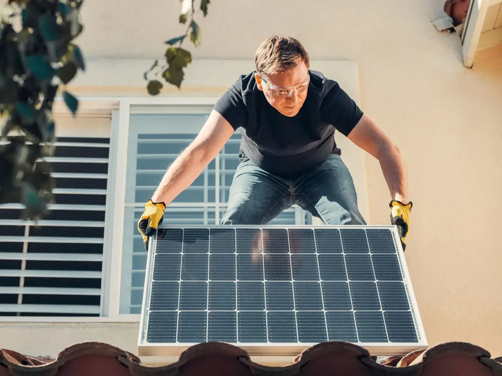 Un hombre instalando un panel solar en el techo de una casa